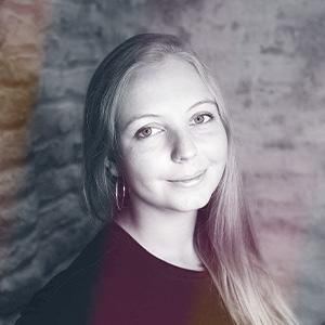 Profesionální portrét Michaely Konopáskové z Astrátexu, blondýnka v burgundském topu se usmívá do kamery