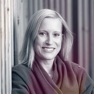 Profesionální portrét Petry Dolejšové, advokátky, usměvavá žena s blond vlasy v burgundském oblečení před bílými sloupy